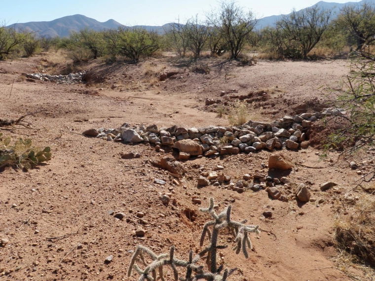 View of newly placed rocks to form check dams across a bare, eroding channel